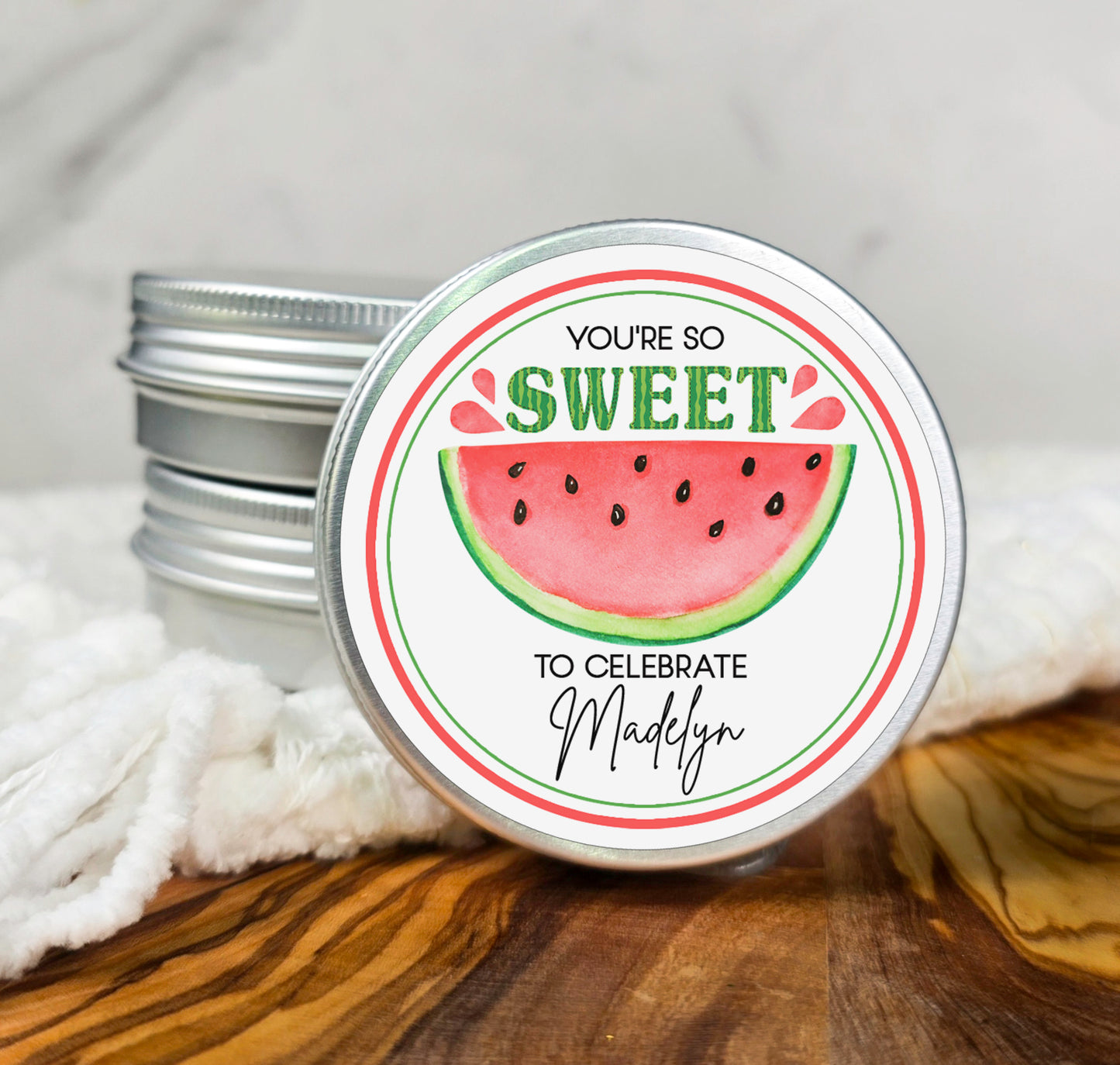 a tin of watermelon lip bale sitting on top of a wooden table