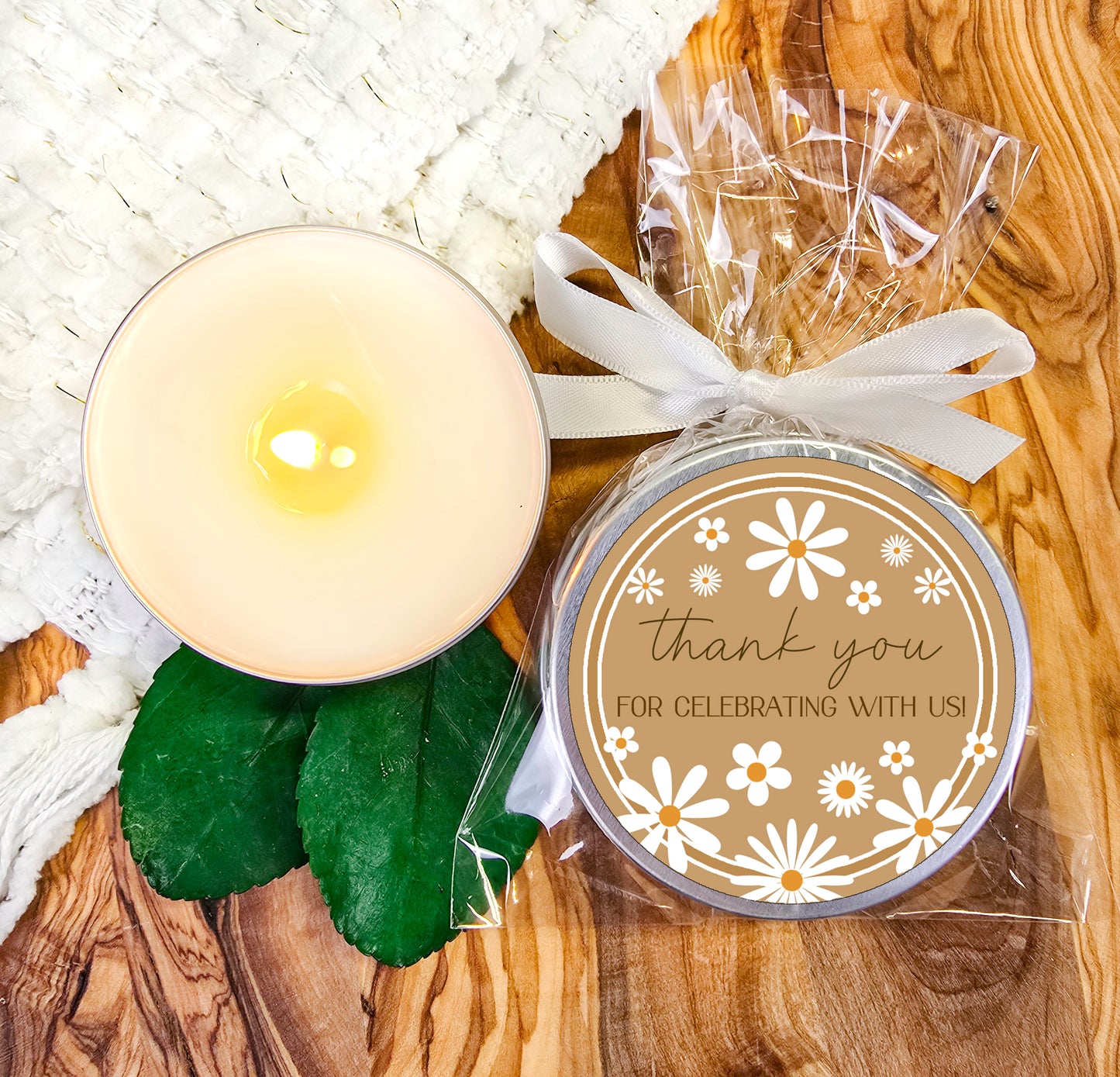 a white candle and some green leaves on a table