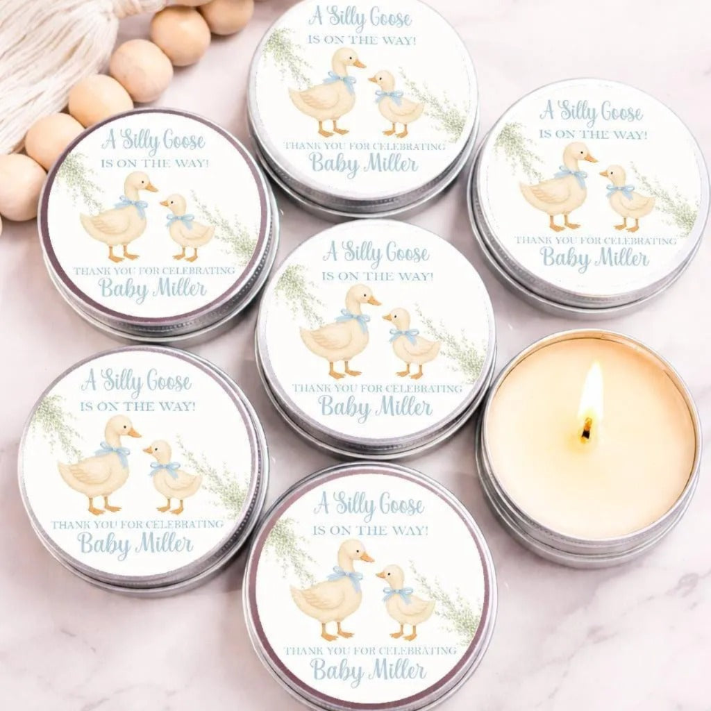 Silly Goose baby shower candle favors with personalized duckling labels in silver tins displayed on marble background.