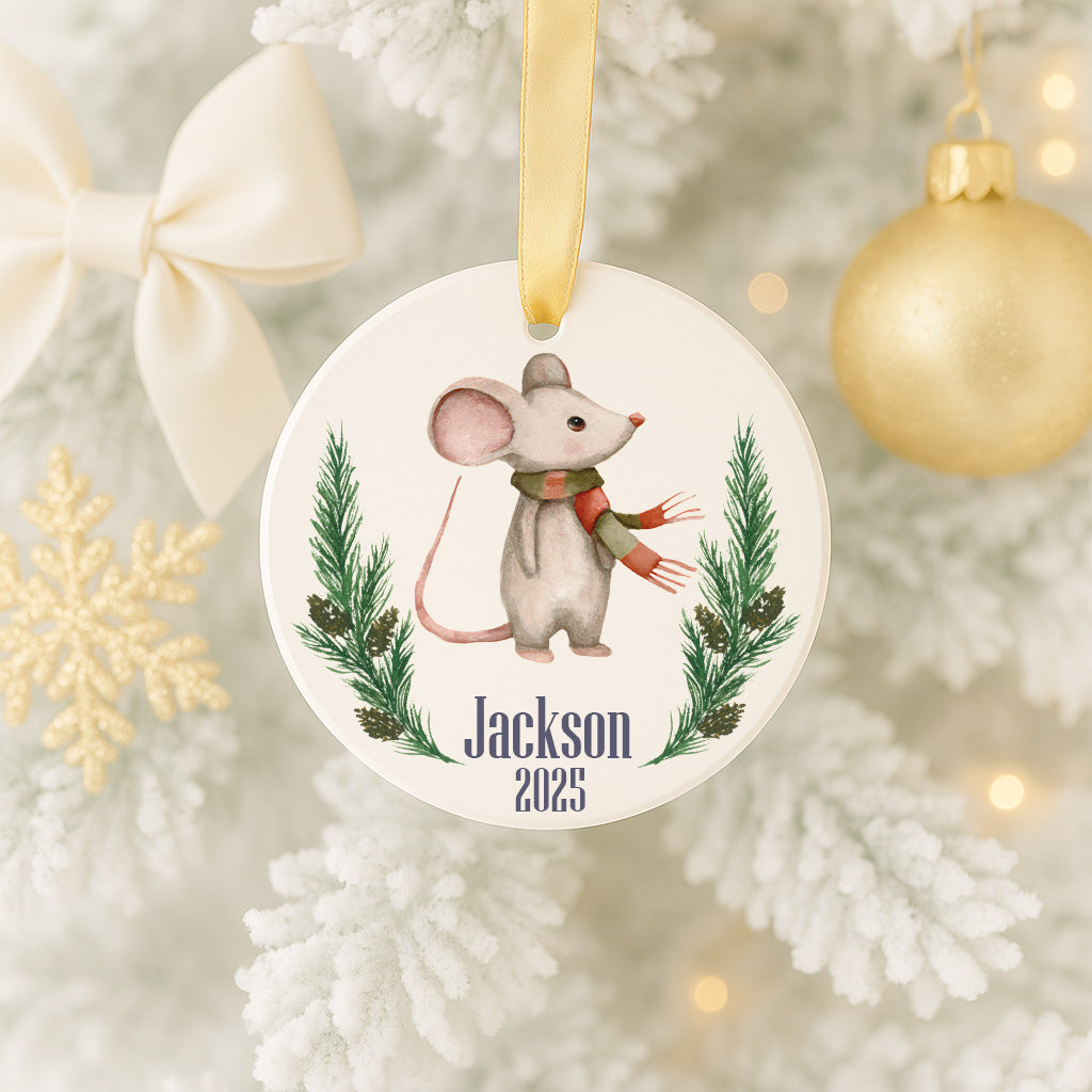 A white Christmas tree decorated with ornaments, including a mouse ornament with a ribbon and a gold ornament.