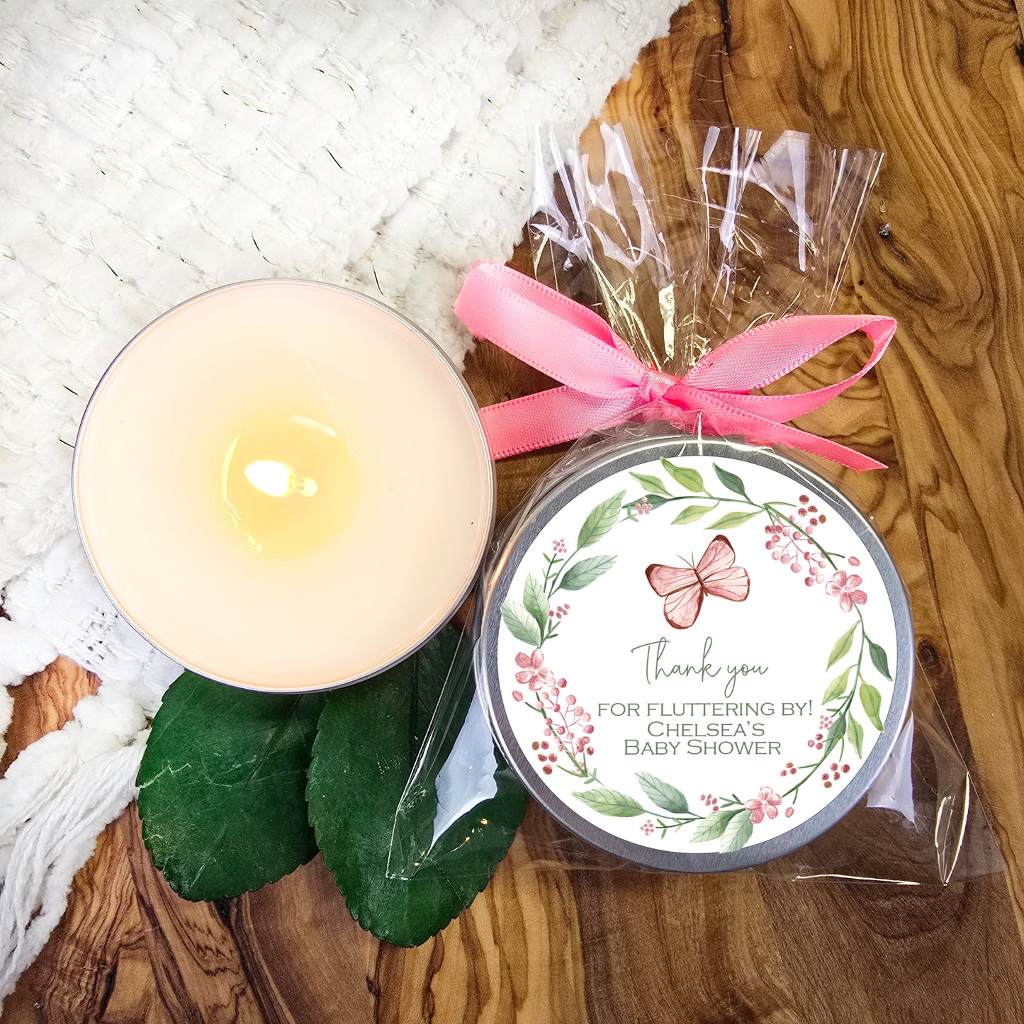 a white candle and a pink ribbon on a wooden table