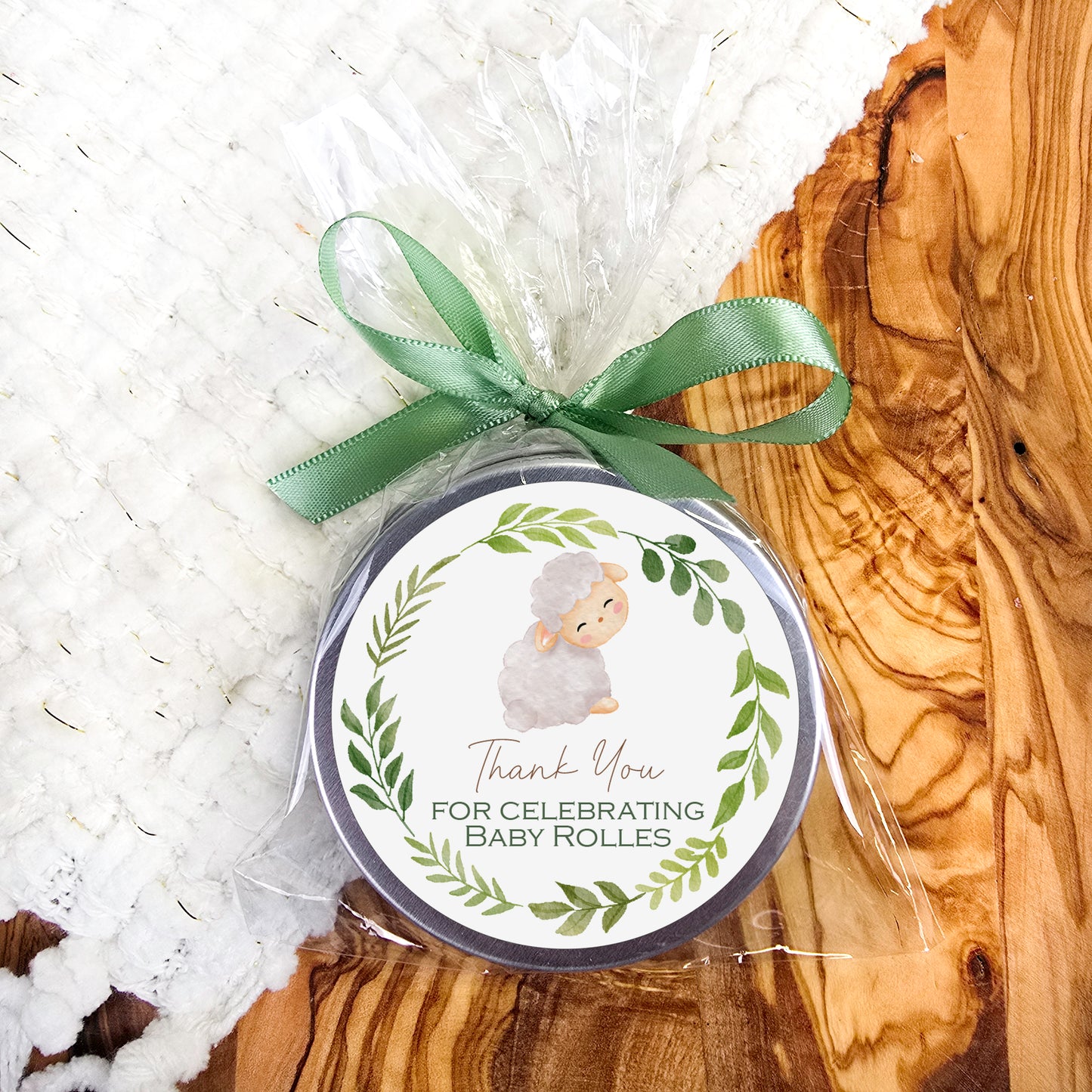 a baby shower tag with a green ribbon on a wooden surface
