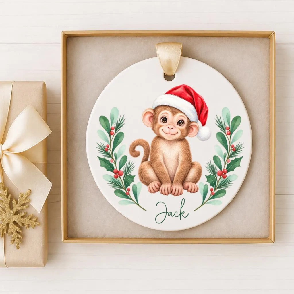 A ceramic ornament featuring a monkey wearing a Santa hat, surrounded by a wreath of greenery and berries, with the name "Jack" written on it.