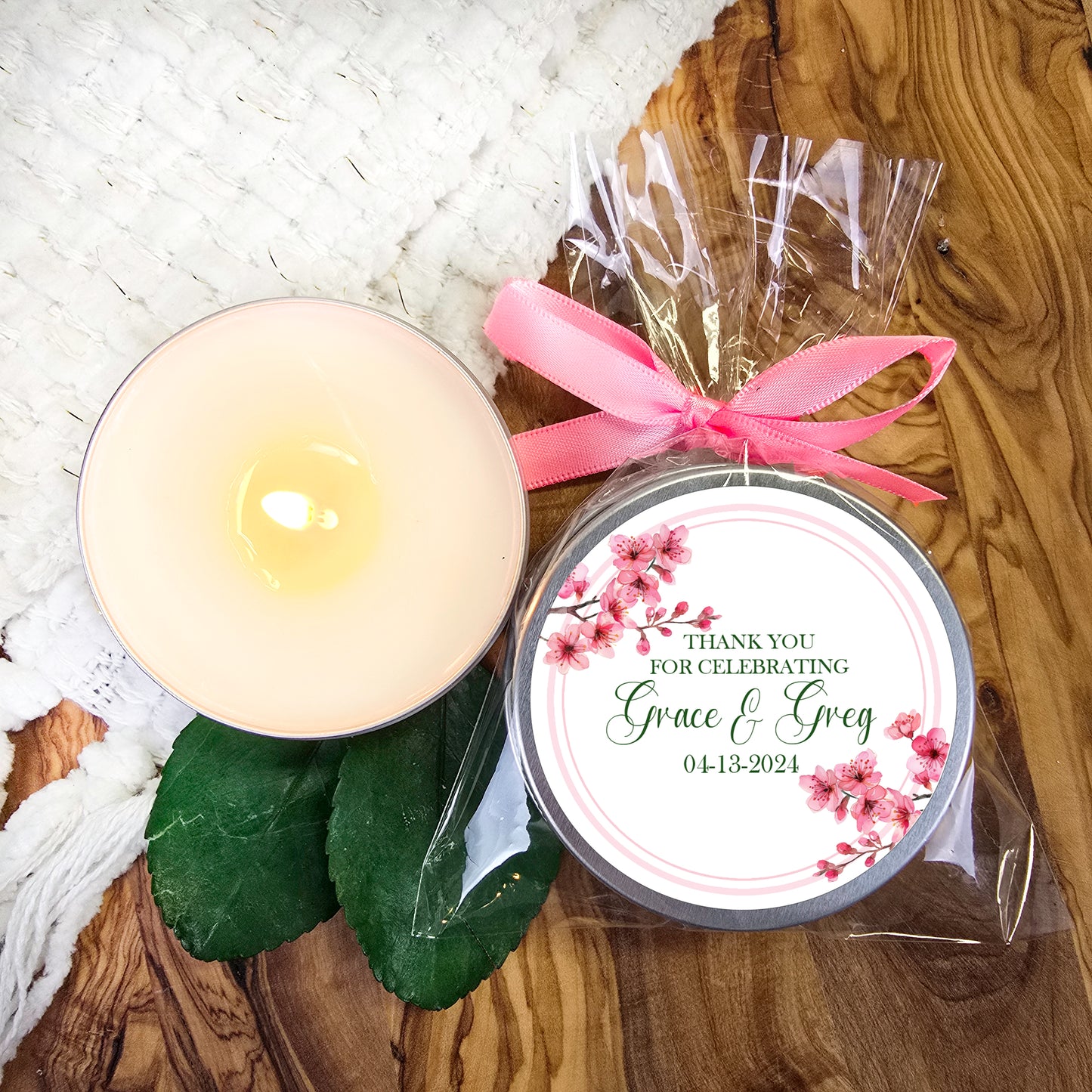 a white candle and a pink ribbon on a wooden table