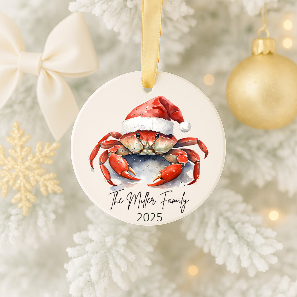 A white ornament with a crab wearing a Santa hat, hanging on a Christmas tree.