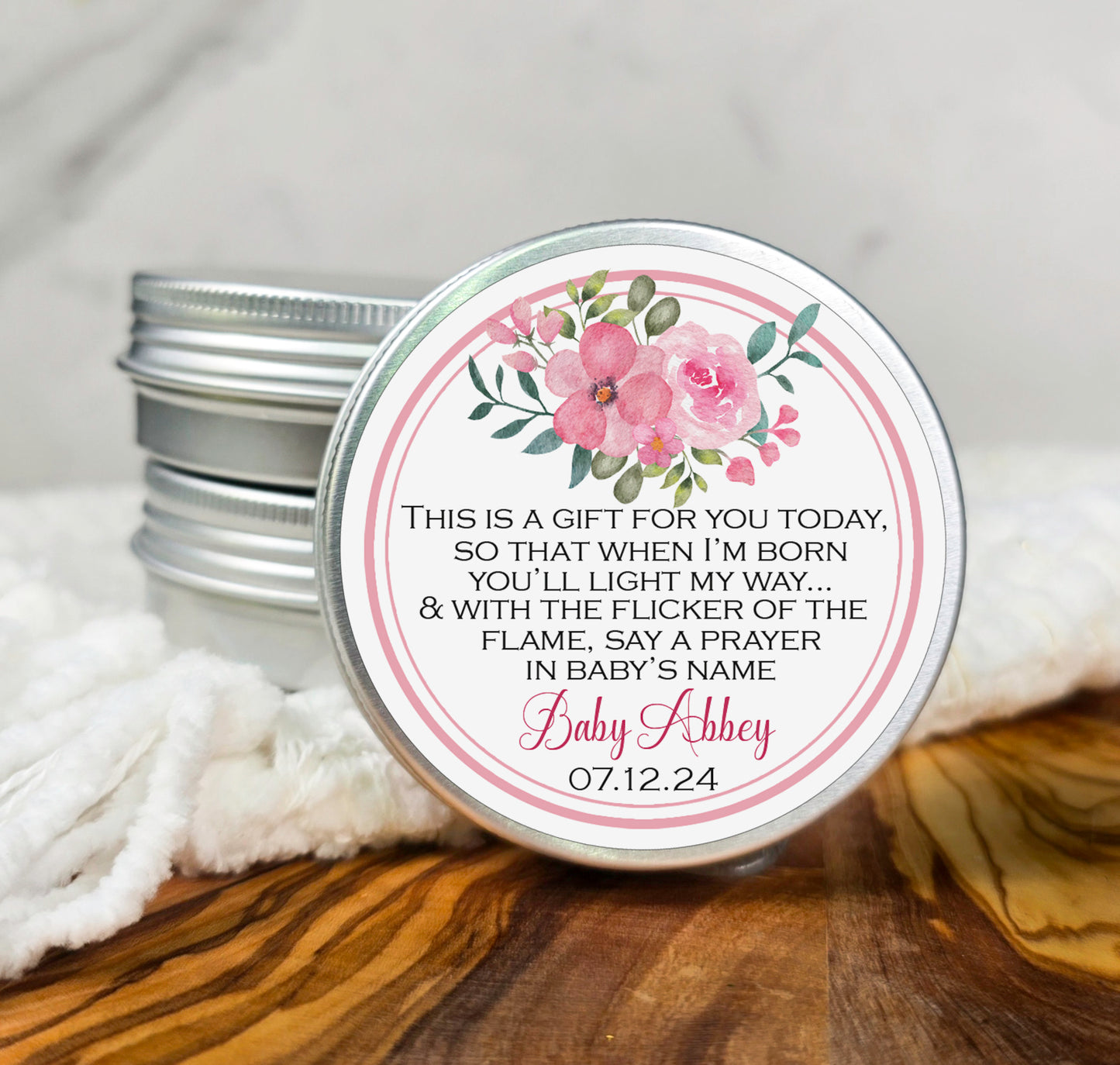 a small tin of personalized candles with a pink flower on it