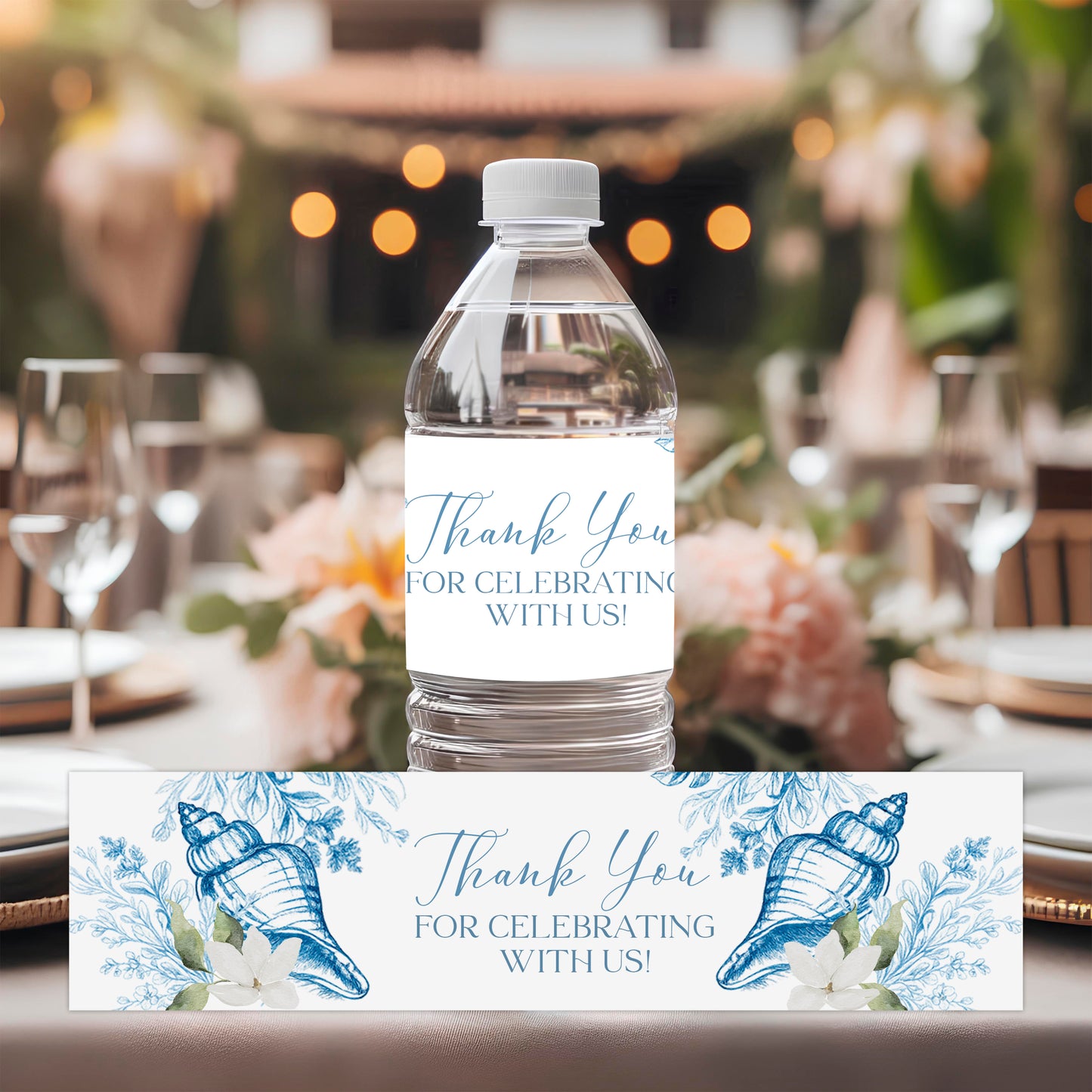 Coastal seashell water bottle labels with blue botanical artwork displayed at an elegant seaside-inspired table setting.