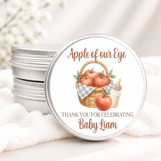 A round tin lid with a label that says "Apple of our Eye" and "Thank you for celebrating Baby Liam".