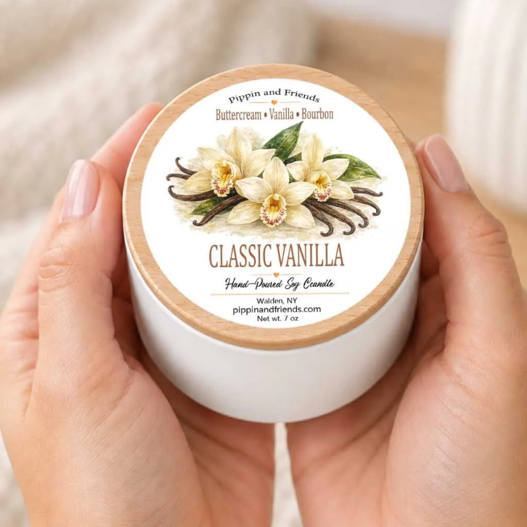 A person's hands holding a white container with a label that features a picture of vanilla flowers and the text "Classic Vanilla" and "Buttercream Vanilla & Bourbon".