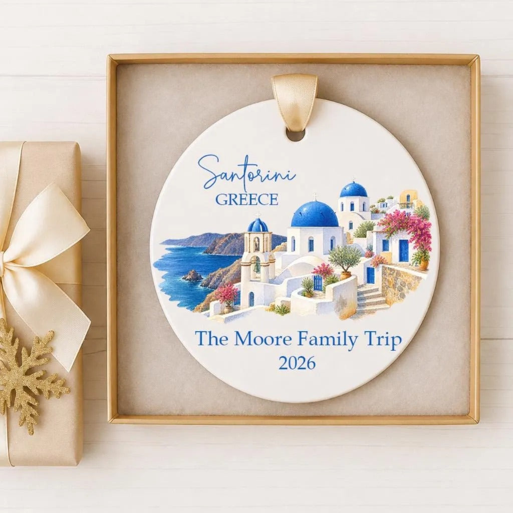 A decorative ornament featuring a scenic view of Santorini, Greece, with the text "Santorini Greece The Moore Family Trip 2026" displayed on it.