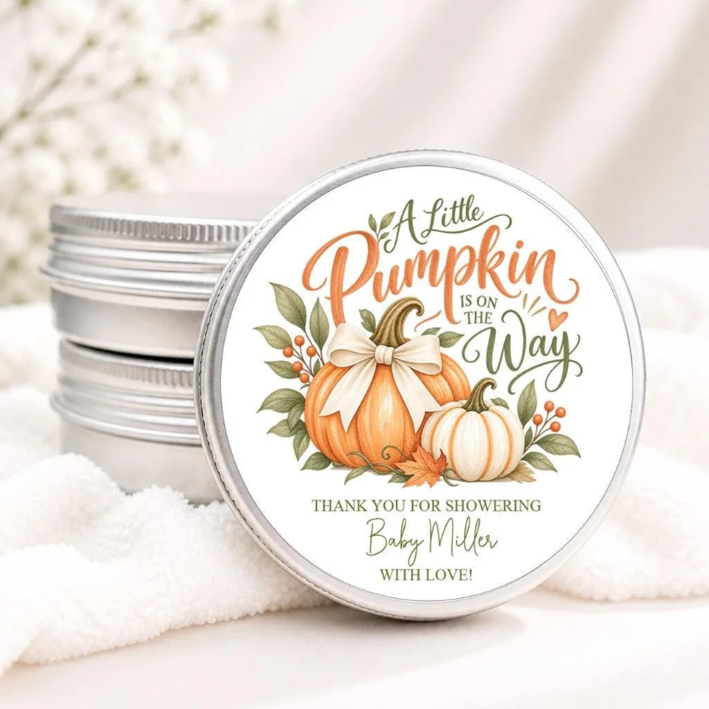 A round tin lid with a decorative design featuring pumpkins and leaves, along with the text "A Little Pumpkin is on the Way" and "Thank you for showering Baby Miller with Love!"