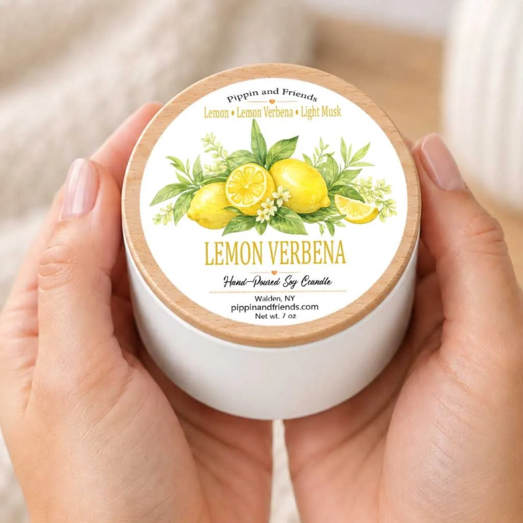 A person's hands holding a white container with a label featuring a lemon and verbena illustration.