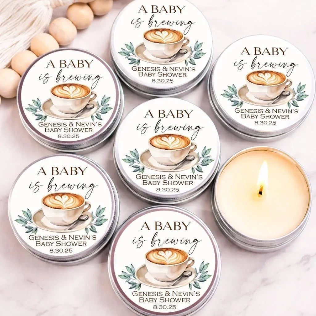 six silver tins arranged on a marble surface, each featuring a label that reads "A BABY is brewing" and includes a coffee cup illustration.