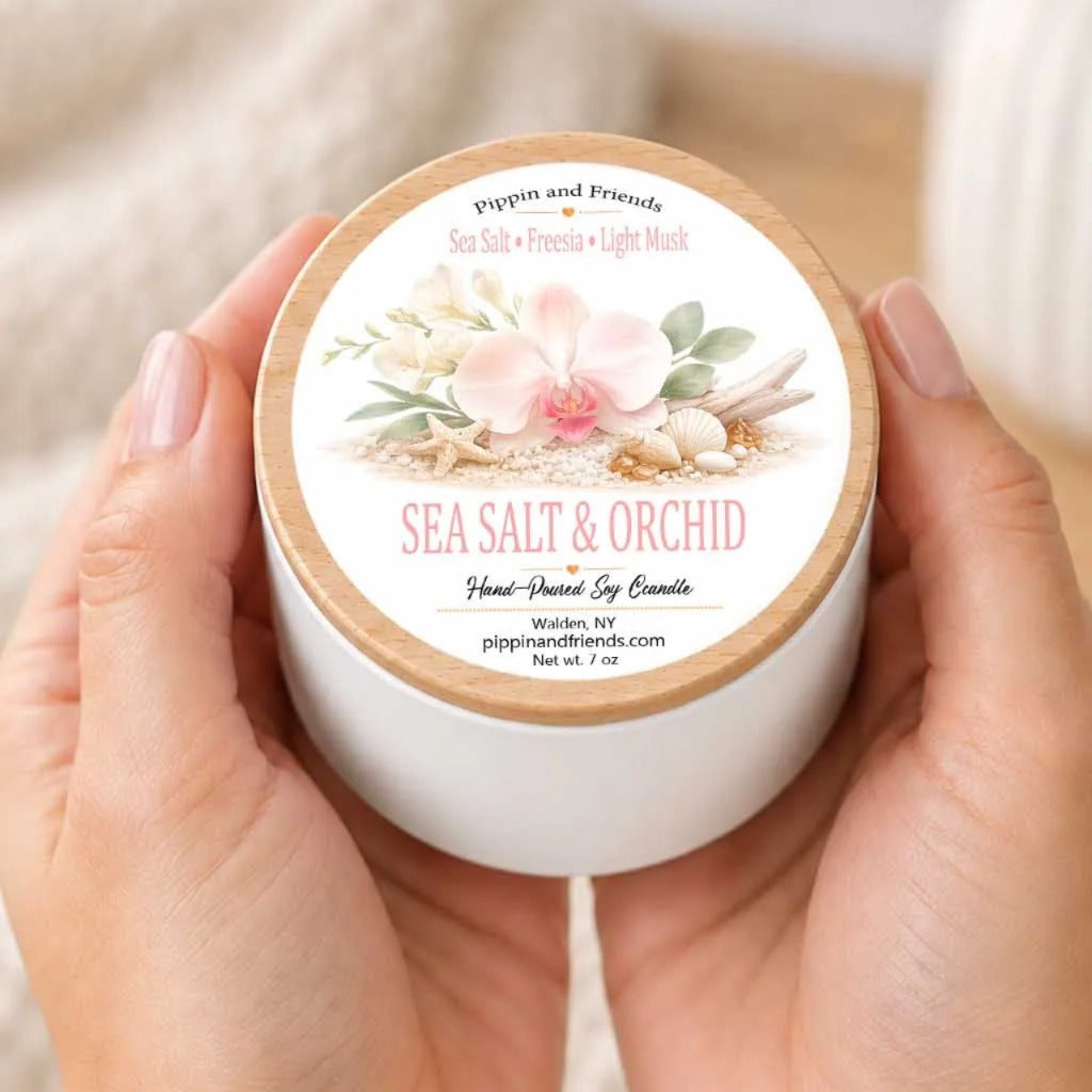 A person's hands holding a white container with a label that reads "Sea Salt & Orchid" and "Poppin and Friends" on it.