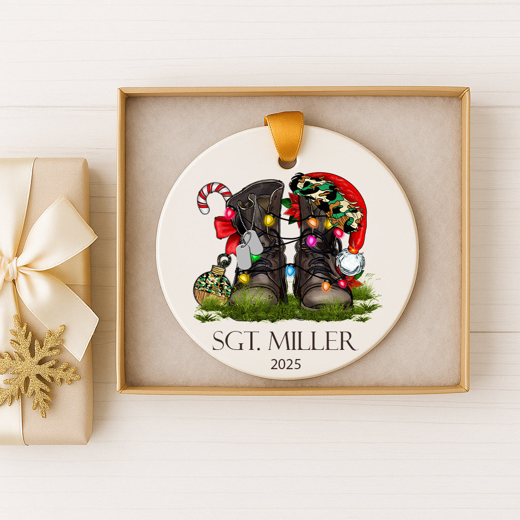 A white ornament with a pair of boots and Christmas lights, placed in a gold box.