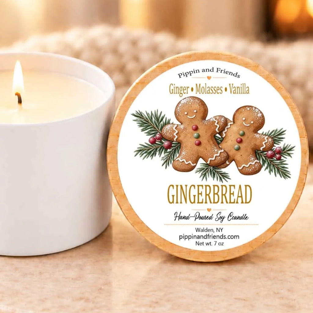A white candle with a gingerbread-themed label next to it, placed on a wooden surface.