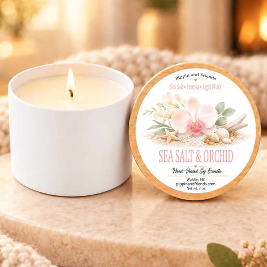 A white candle with a label next to it, both placed on a beige surface.