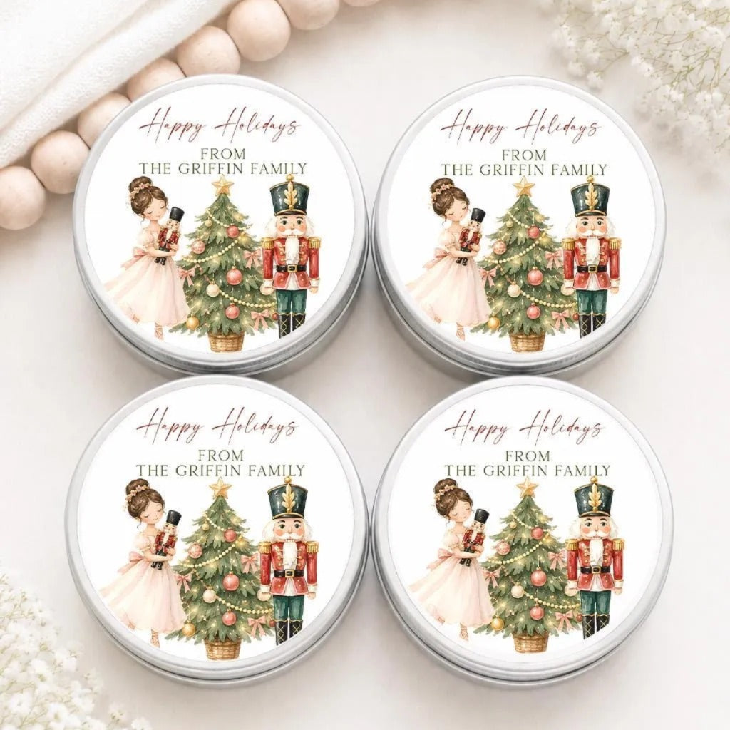four round tin cans with holiday-themed labels, featuring illustrations of a woman in a pink dress and a nutcracker, along with Christmas trees and ornaments.