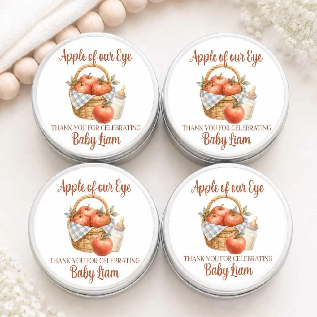 four round tin labels with a design of a basket filled with apples and a baby bottle, along with text that says "Apple of our Eye" and "Thank you for celebrating Baby Liam".
