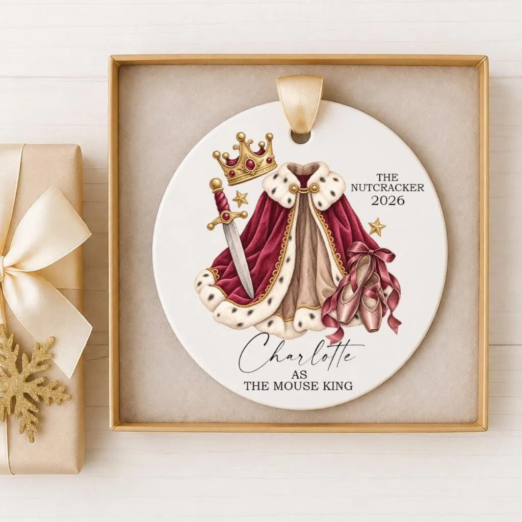 A decorative ornament featuring a crown, a red cape, and a sword, along with the text "The Nutcracker 2026" and "Charlotte as the Mouse King".