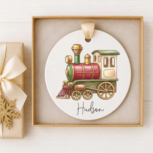 A white oval ornament with a red and green train engine, displayed in a gold frame.