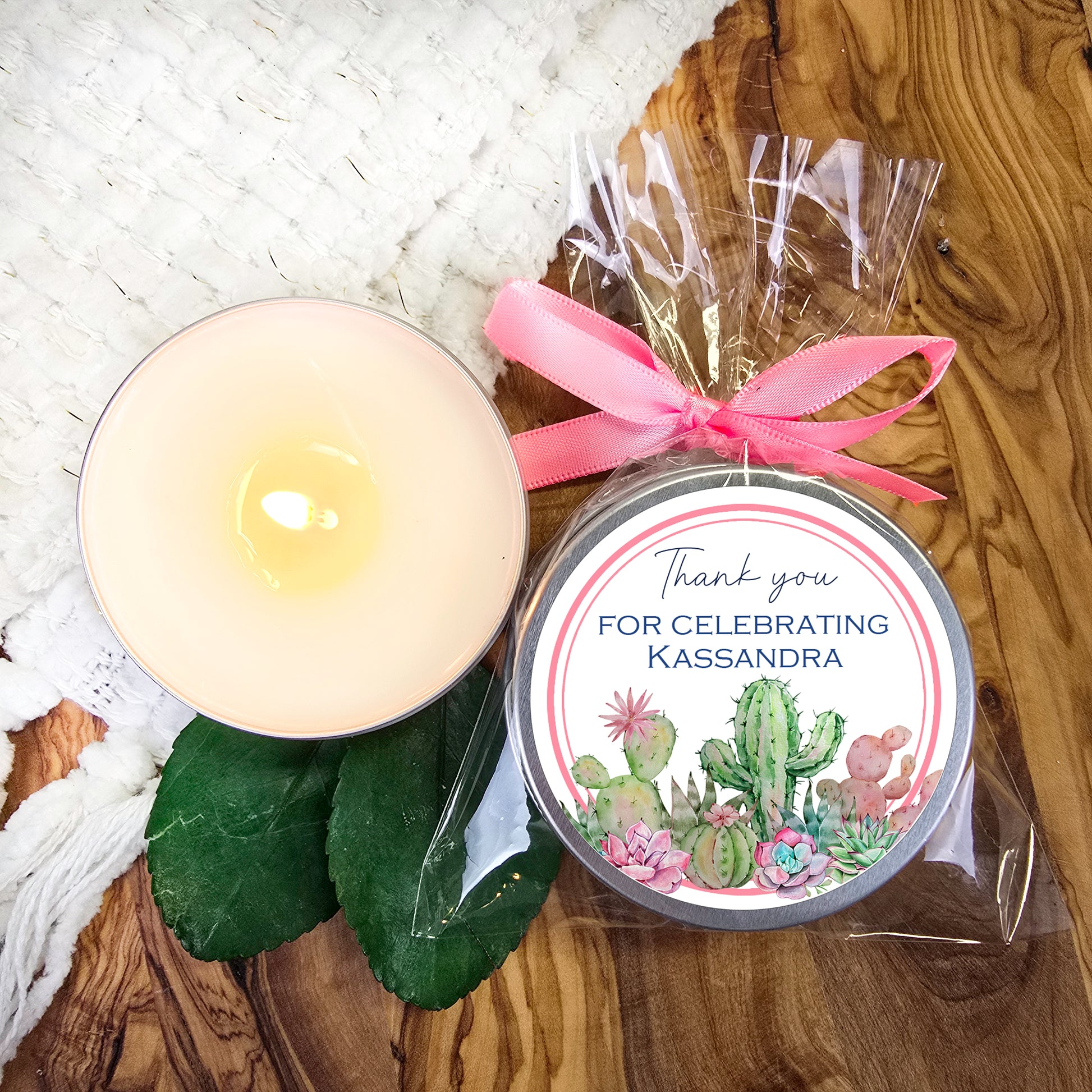 a white candle and a pink ribbon on a wooden table