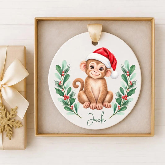 A ceramic ornament featuring a monkey wearing a Santa hat, surrounded by a wreath of greenery and berries, with the name "Jack" written on it.