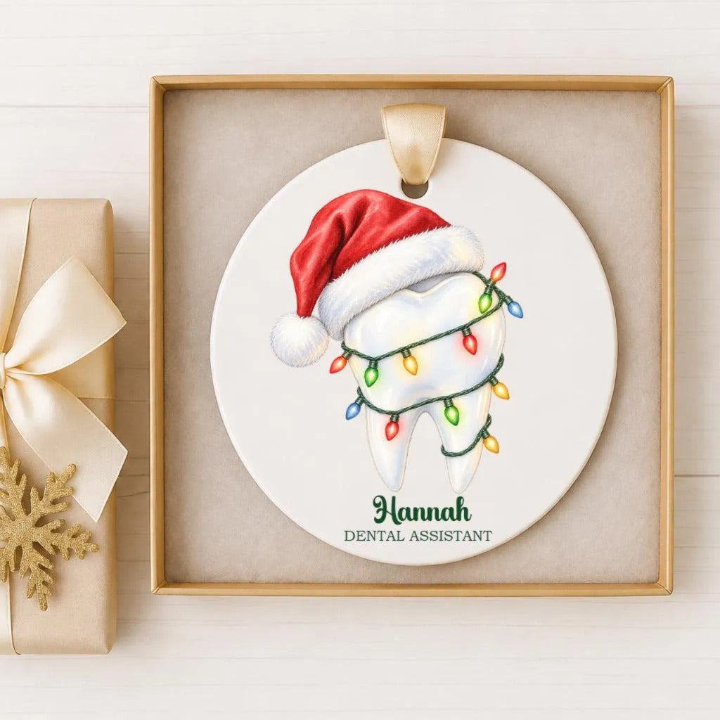 A ceramic ornament in a wooden frame, featuring a tooth with a red Santa hat and colorful Christmas lights around it.