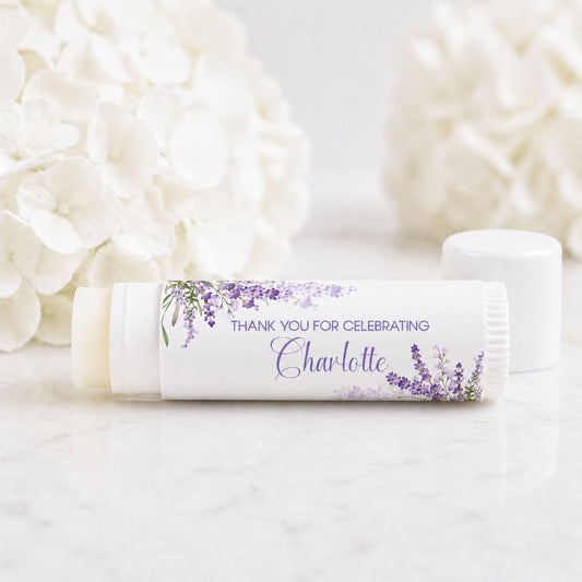 Set of 12 personalized lavender lip balm favors with purple floral labels reading thank you for celebrating Charlotte on white tubes