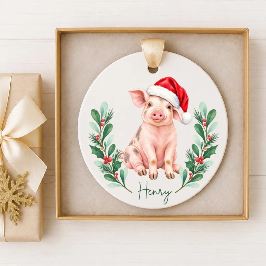 A ceramic ornament featuring a pig wearing a Santa hat, surrounded by holly leaves and berries, with the name "Henry" written below.