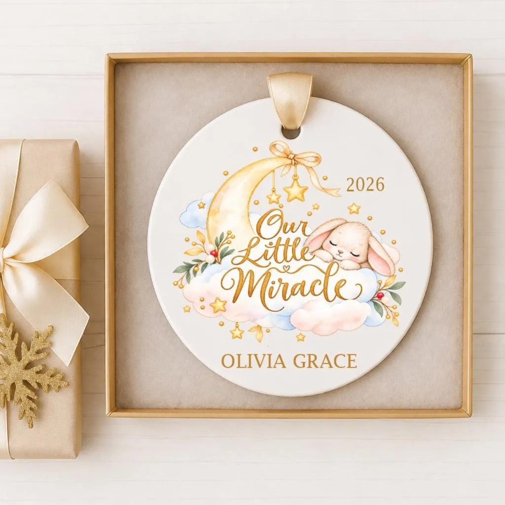 A white ceramic ornament with a gold design, featuring a sleeping bunny and a crescent moon, is displayed in a gold box.