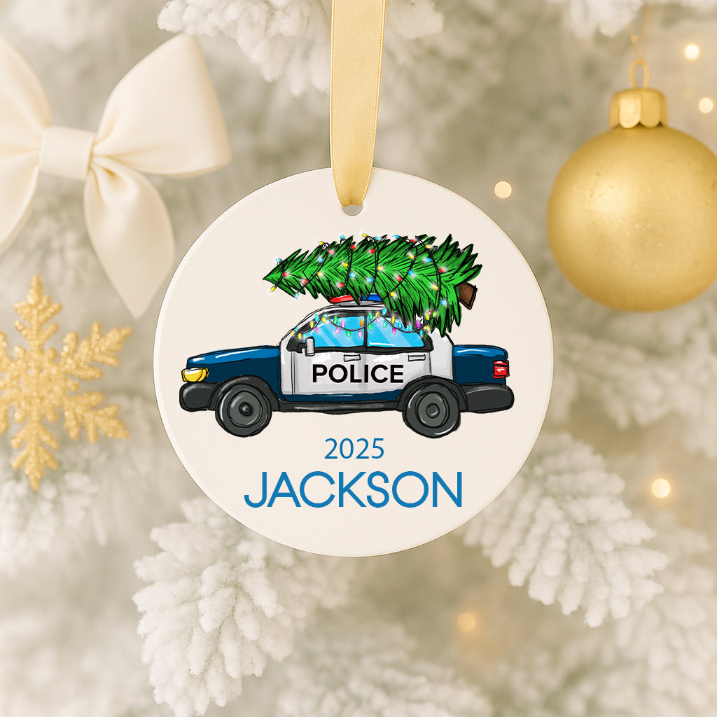 A Christmas ornament featuring a police car with a Christmas tree on top, hanging on a tree.