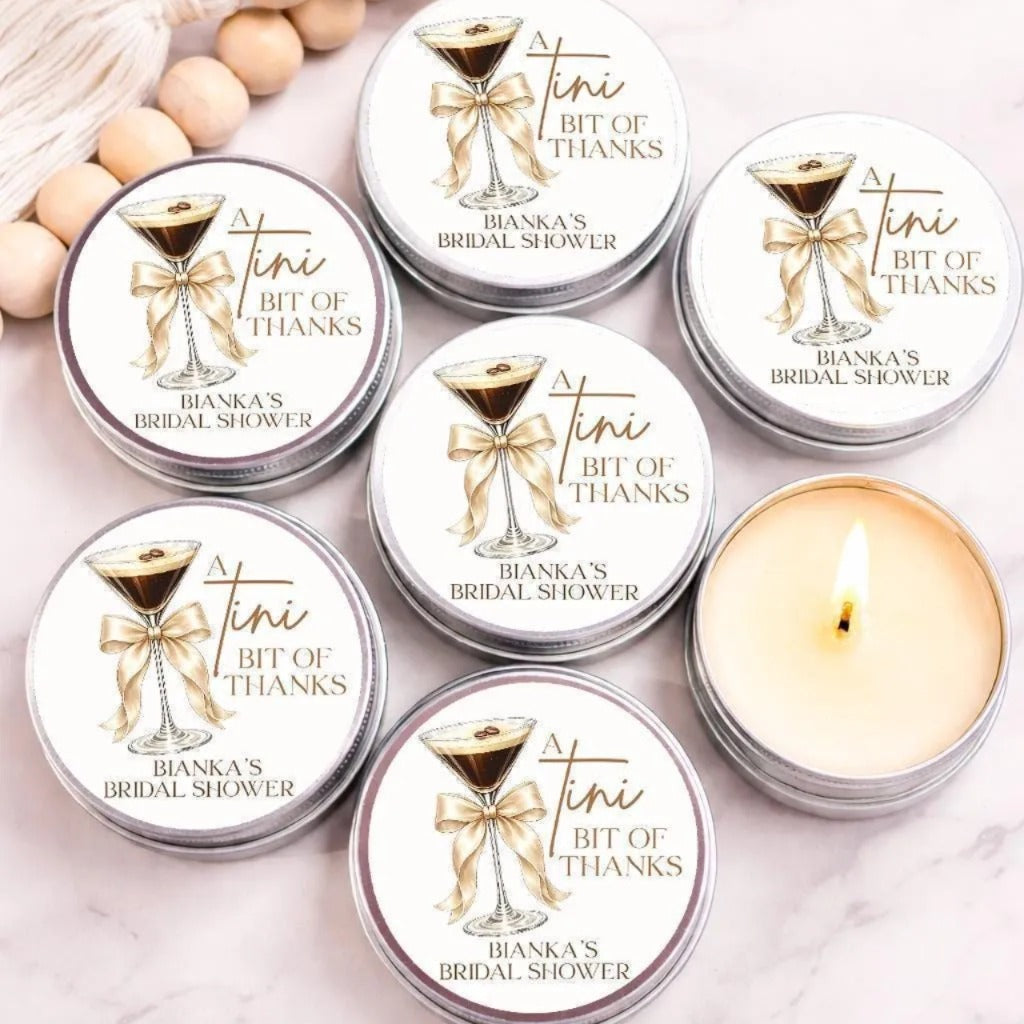 a collection of round tin cans with a label that reads "A Tini Bit of Thanks" and "Bianca's Bridal Shower". The cans are arranged on a marble surface, with a lit candle in one of them.