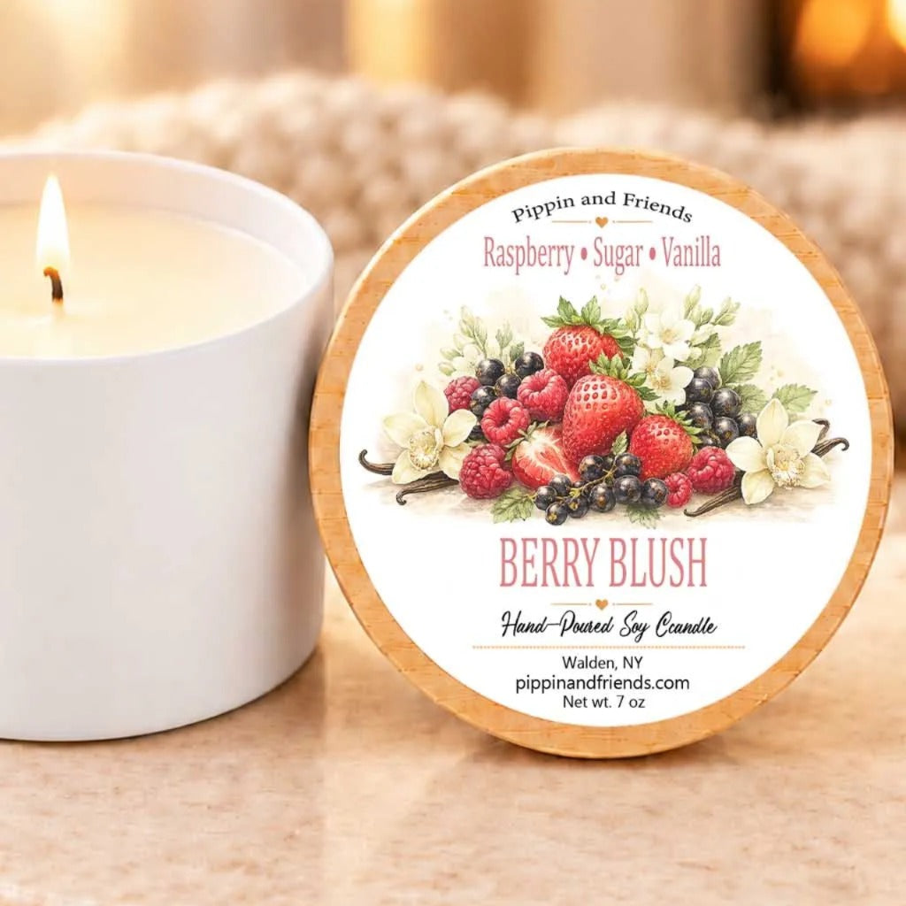 A white candle with a label that reads "Berry Blush Hand-Poured Soy Candle" next to it, with a blurred background.