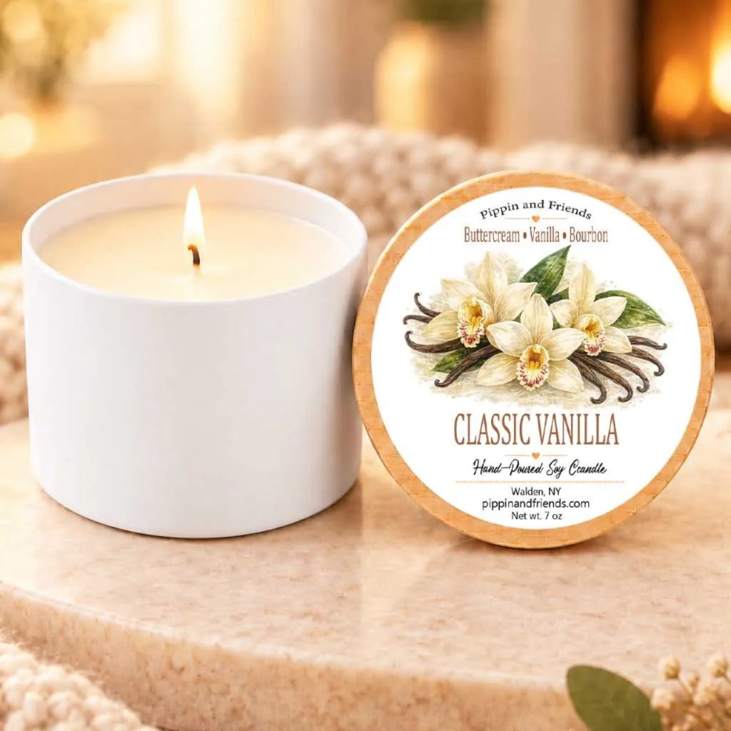a white candle labeled "Classic Vanilla" next to a white candle holder, both sitting on a wooden surface.