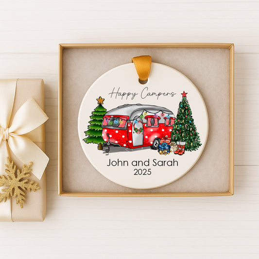 A white ornament with a red and white camper van, Christmas trees, and presents, along with the text "Happy Campers" and "John and Sarah" and the year "2025".