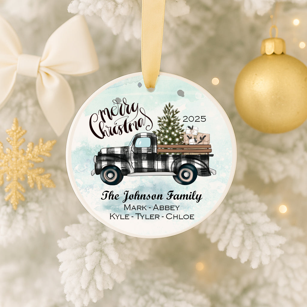 A Christmas ornament featuring a black and white checkered truck with a Christmas tree and presents on the back, hanging on a tree.