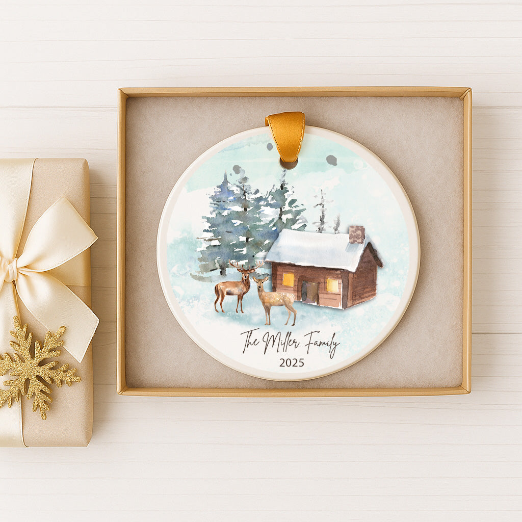 A decorative ornament featuring a cabin and deer in a snowy winter landscape, with the text "The Miller Family" and the year "2025" displayed.