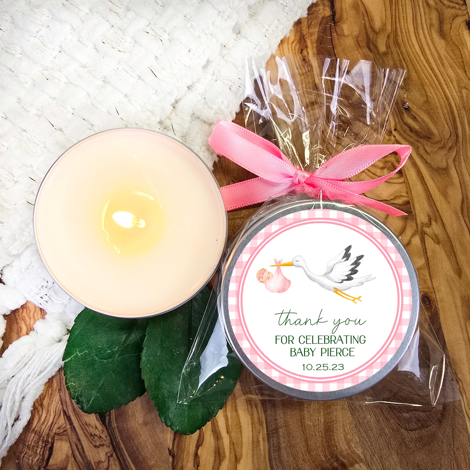 a candle with a pink ribbon on a table
