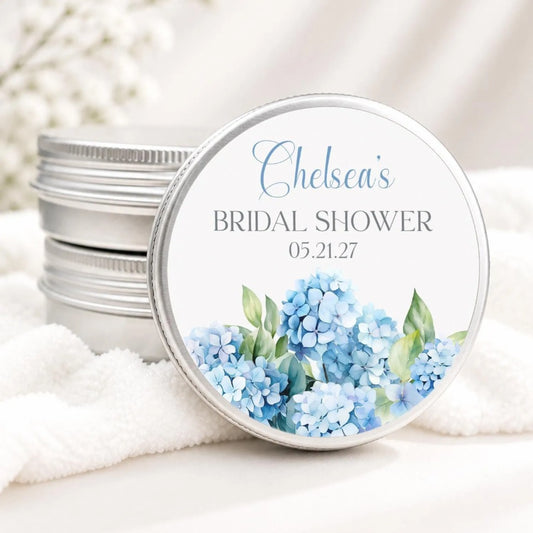 A round tin with a floral design and text on it, placed on a white cloth.