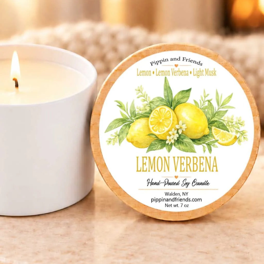 A white candle with a label that reads "Lemon Verbena" and "Hand-Drenched Soy Candle" next to it.