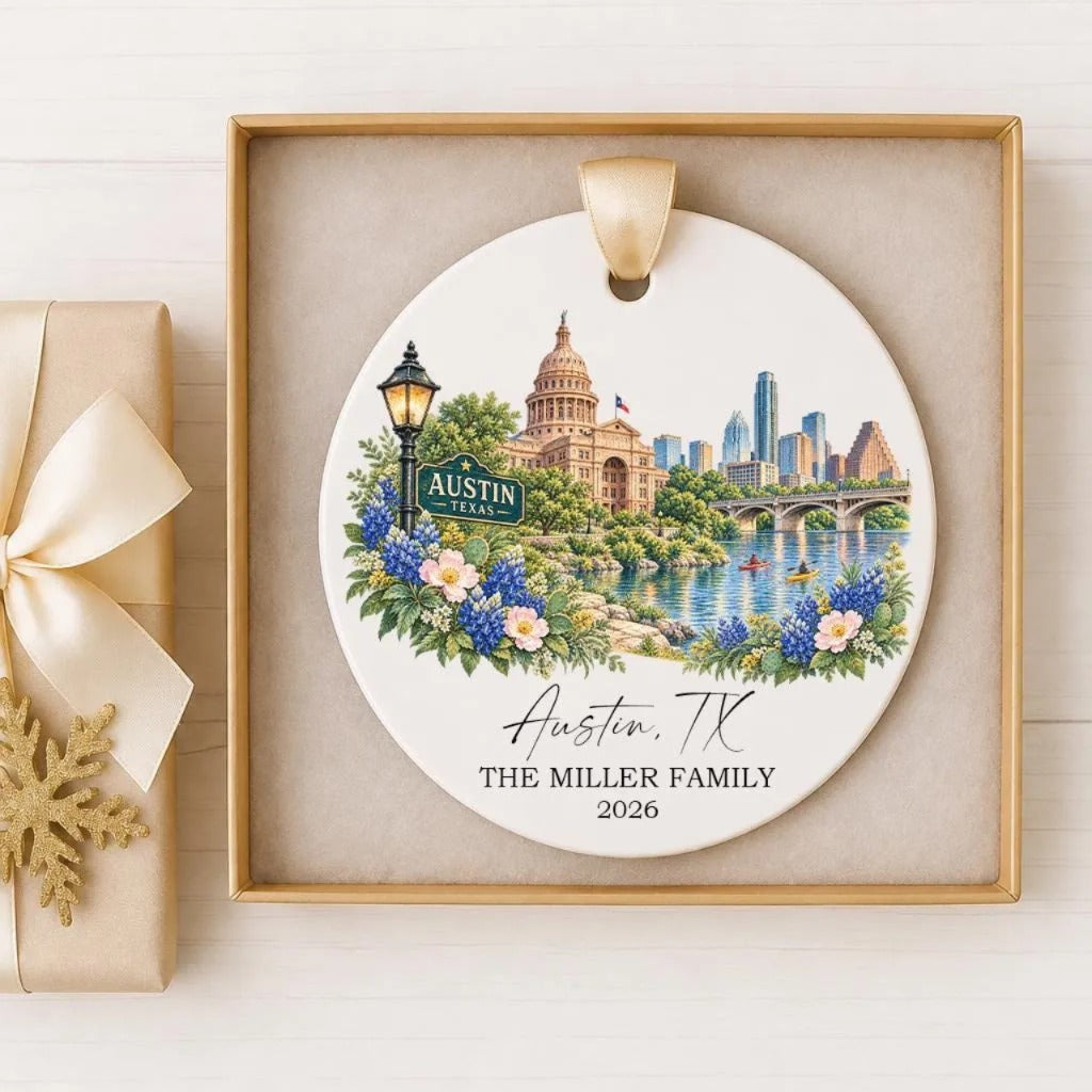 A decorative ornament featuring a cityscape of Austin, Texas, with a lamppost, flowers, and a body of water in the foreground.