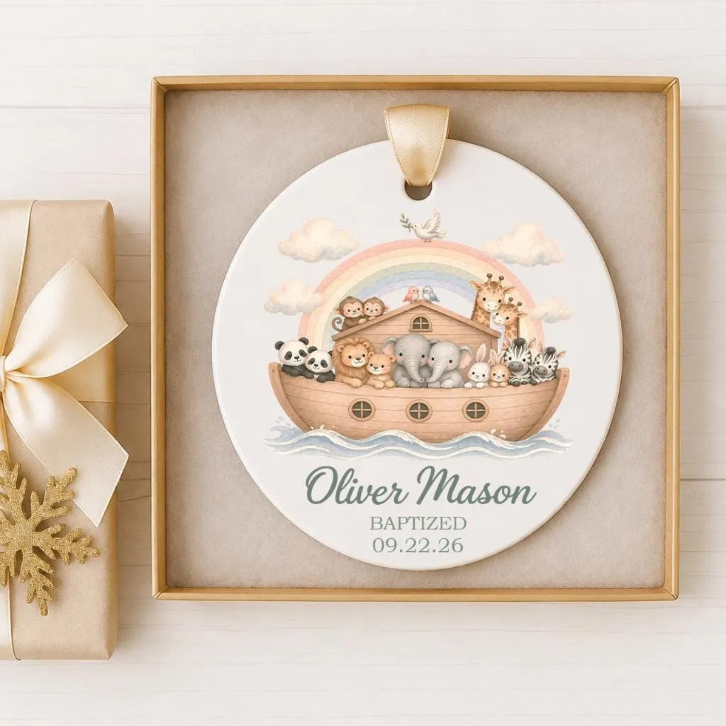 A christening or baby shower ornament featuring a boat with various animals, including elephants, giraffes, and pandas, floating on a rainbow-colored body of water.