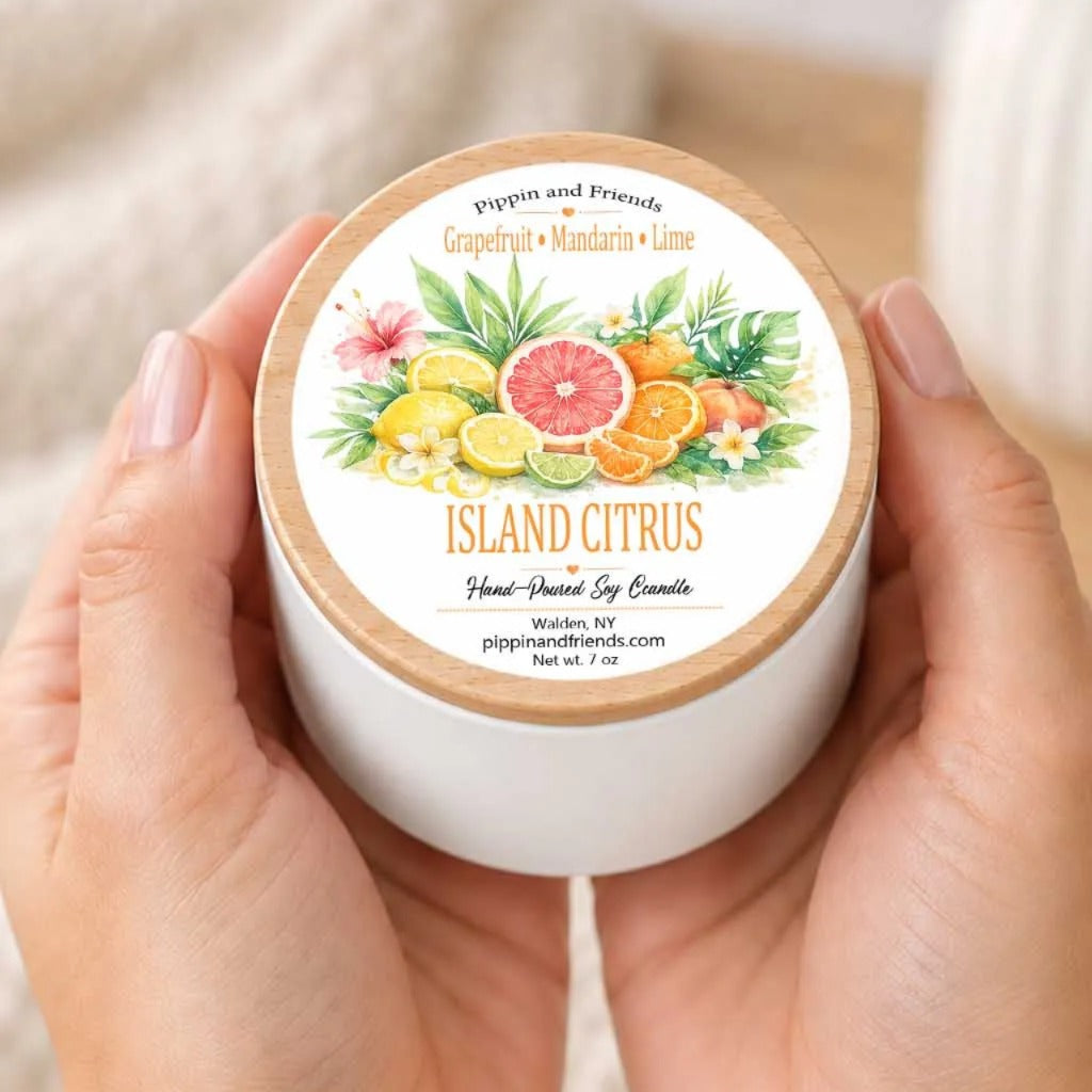 A person's hands holding a white container with a label featuring an illustration of citrus fruits and flowers.