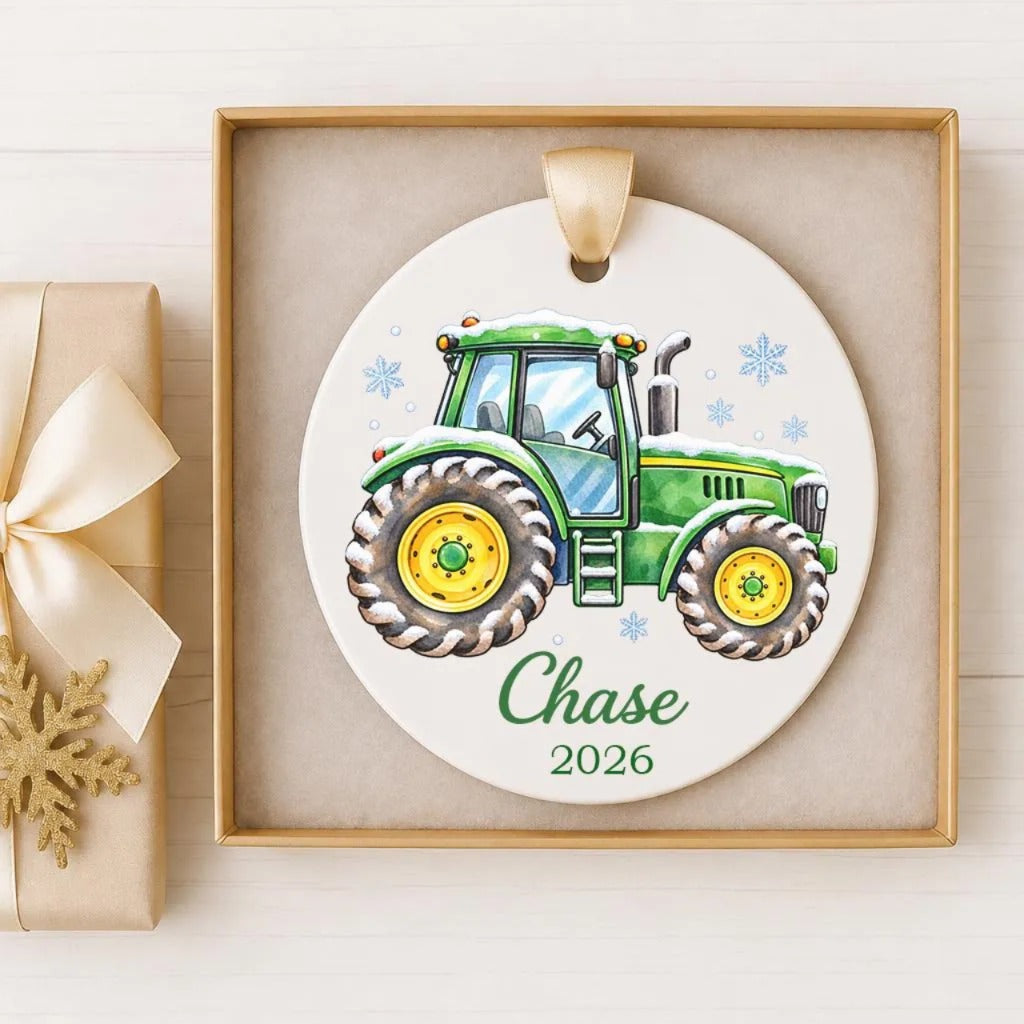 A white ornament with a green tractor illustration on it, hanging in a wooden frame.
