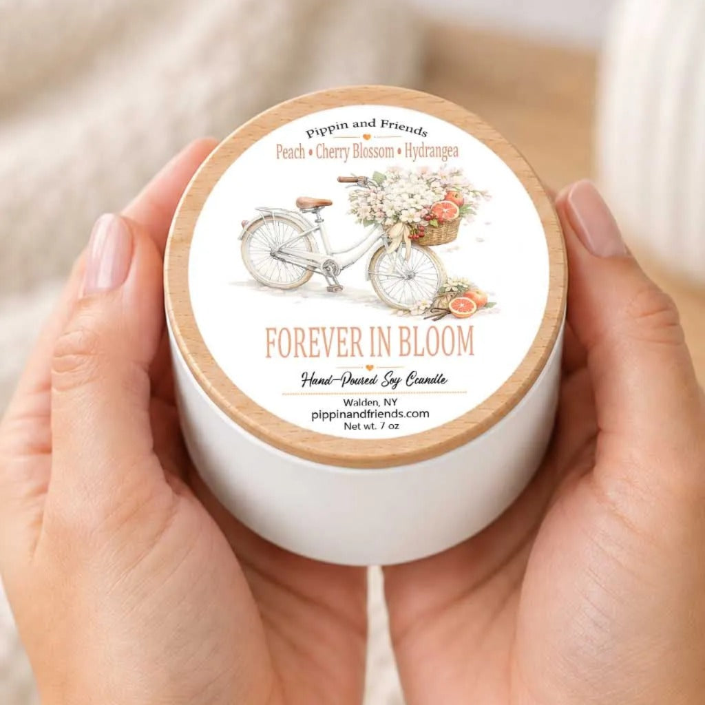 A person's hands holding a white container with a label featuring an illustration of a bicycle and flowers.