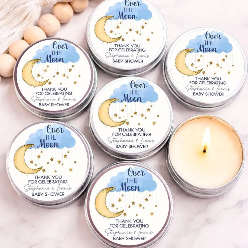 a collection of six candles with a moon and star motif, arranged on a marble surface. The candles are labeled as "Over the Moon" and "Thank you for celebrating Stephanie & Ian's Baby shower".