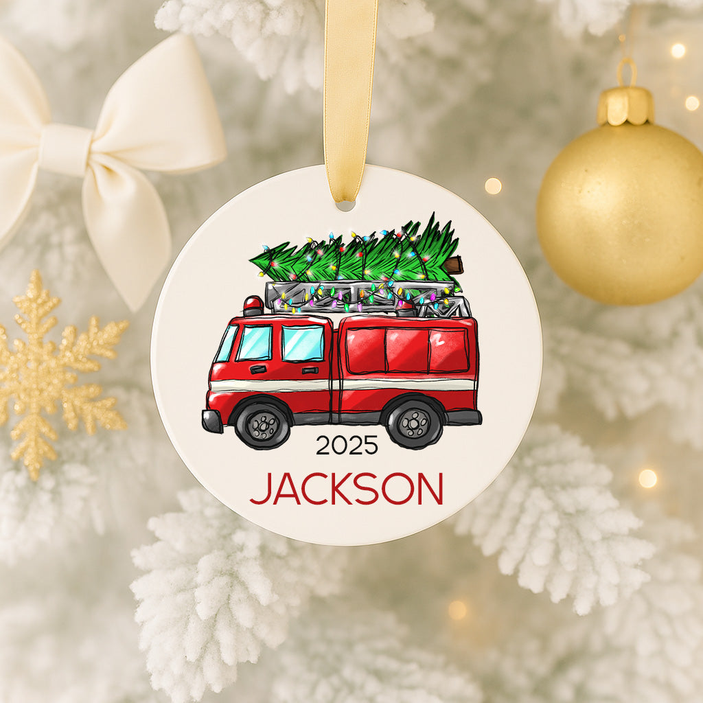 A Christmas ornament featuring a red fire truck carrying a Christmas tree, with the name "Jackson" written below it.