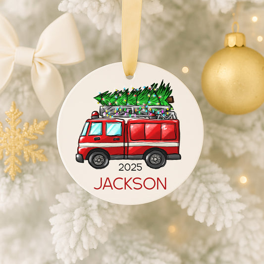 A Christmas ornament featuring a red fire truck carrying a Christmas tree, with the name "Jackson" written below it.