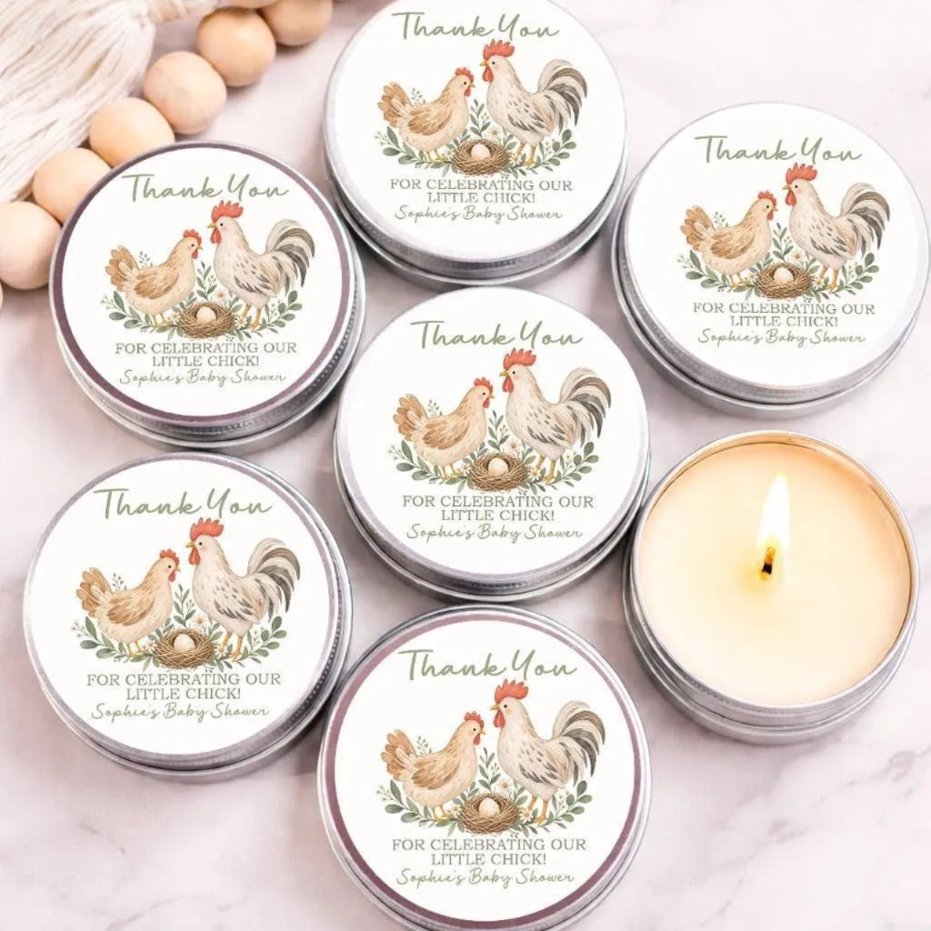 six silver tin candles with white labels, each featuring a rooster and a nest, arranged on a marble surface.